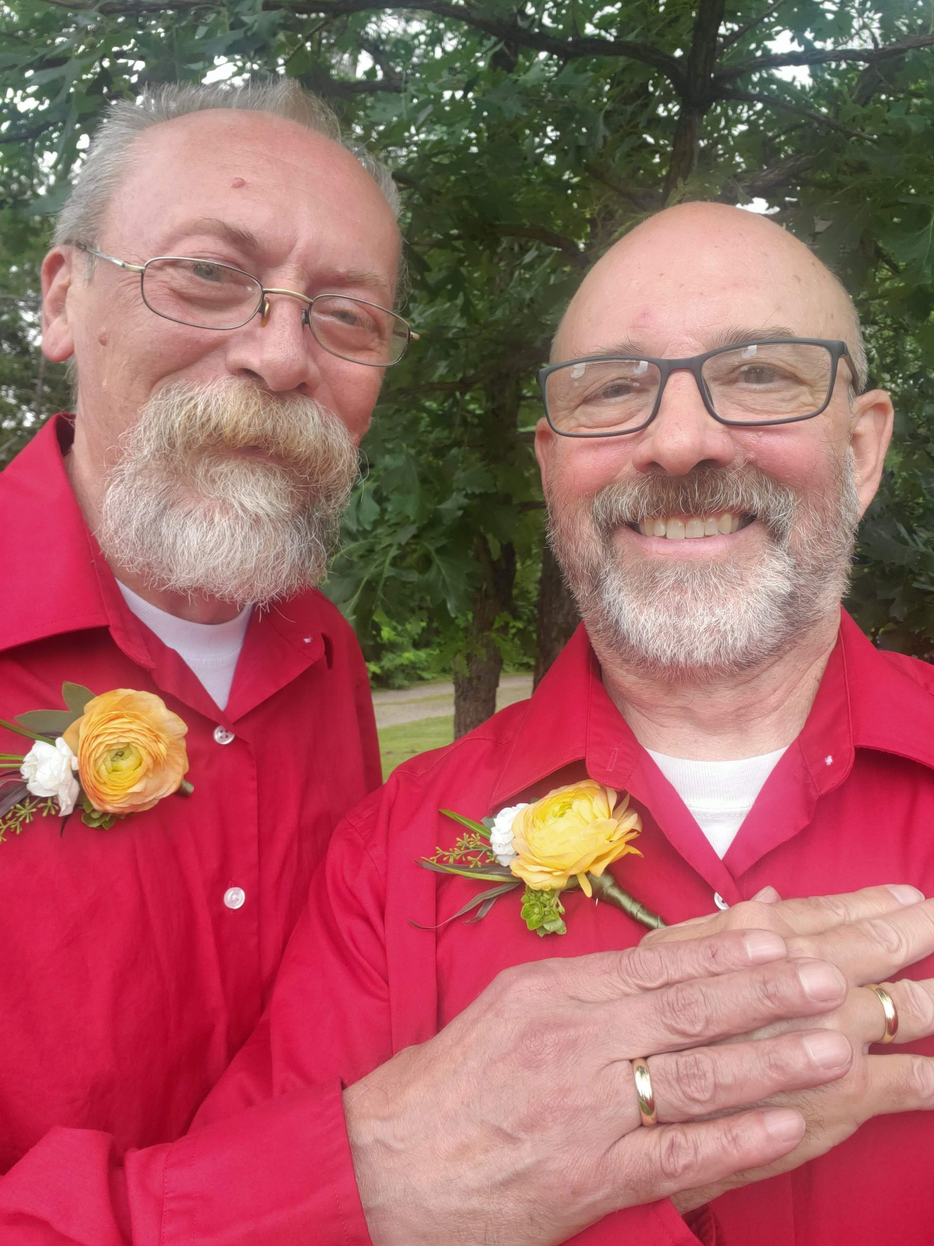 Two men wearing red shirts and glasses are posing for a picture.