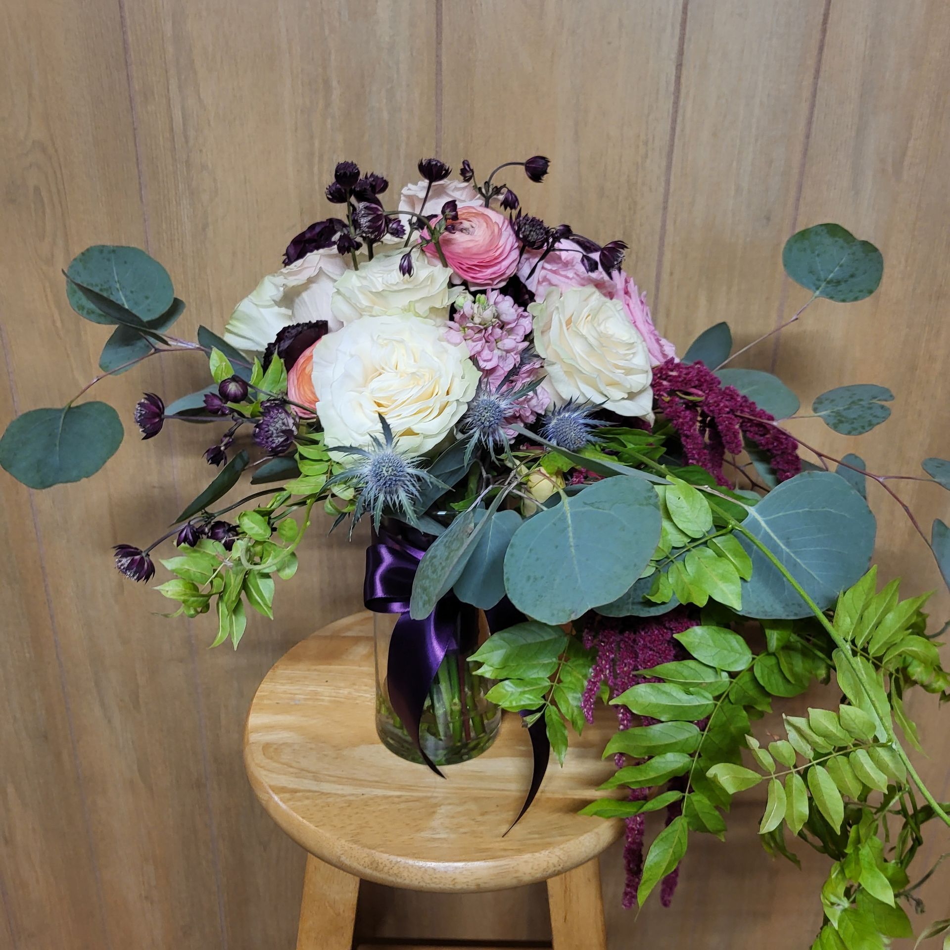 A bouquet of pink and white flowers on a wooden stool.