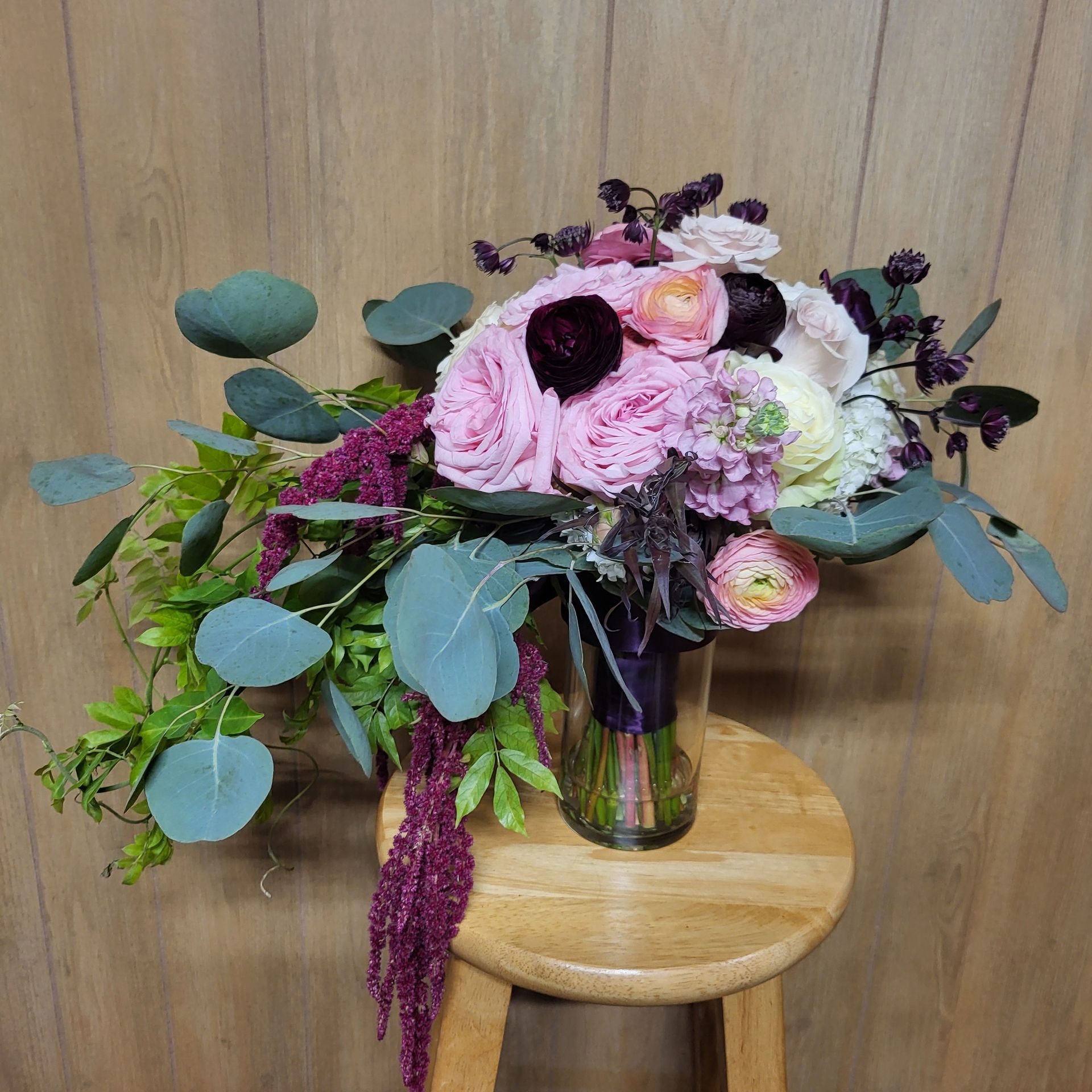 A bouquet of flowers is sitting on a wooden stool.