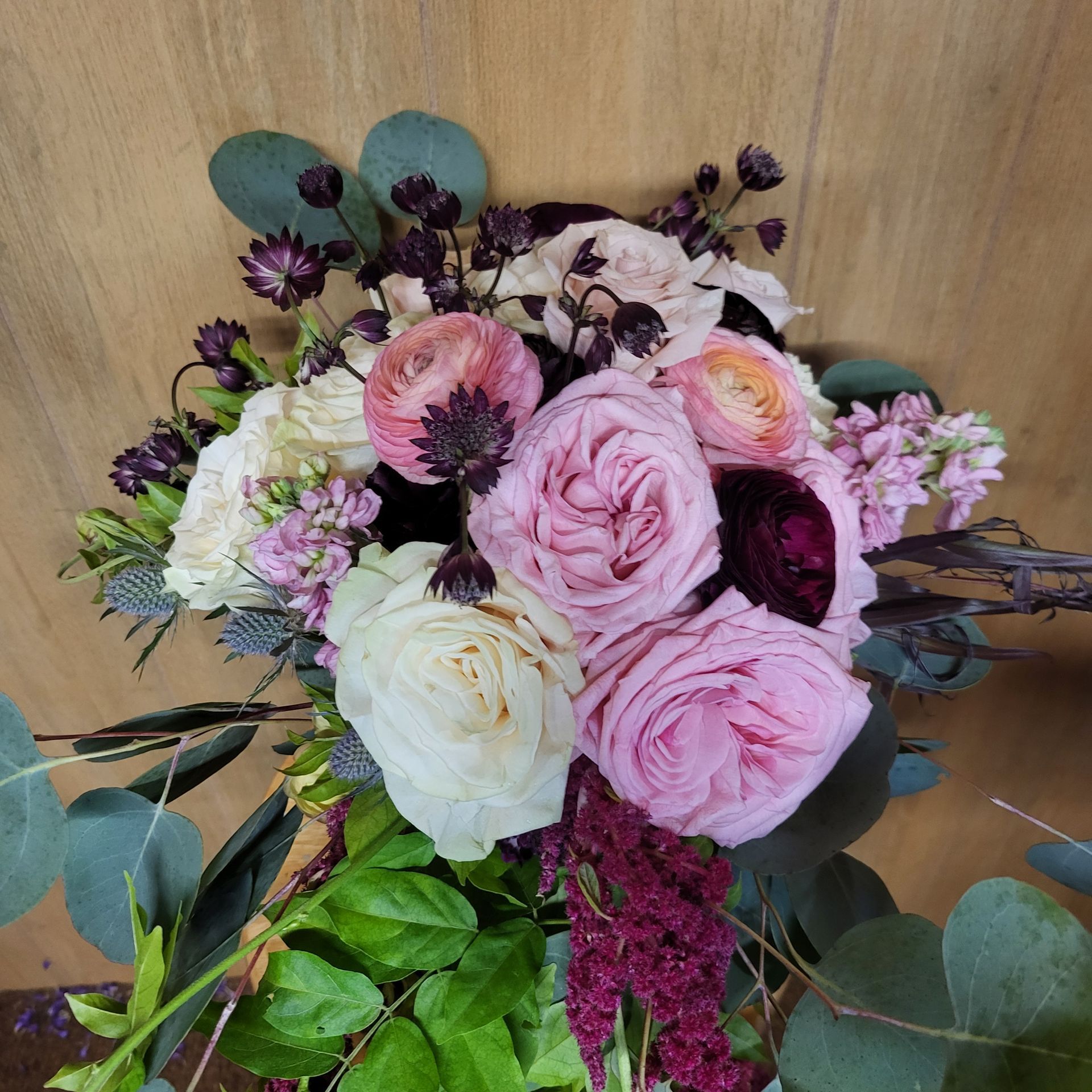 A bouquet of pink and white flowers is sitting on a wooden table.