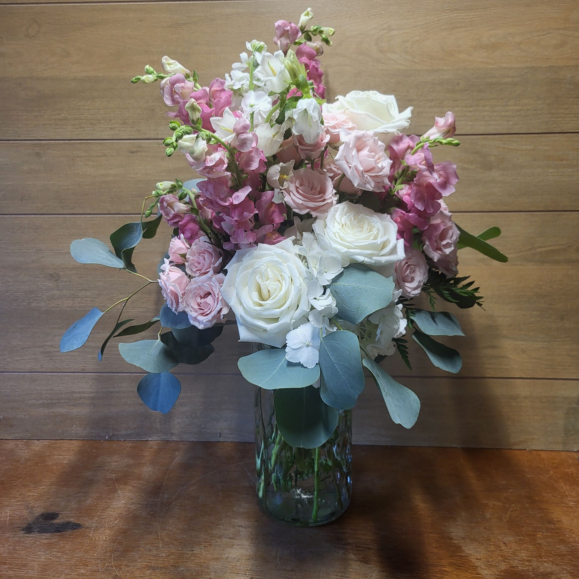A bouquet of pink and white flowers on a wooden stool.