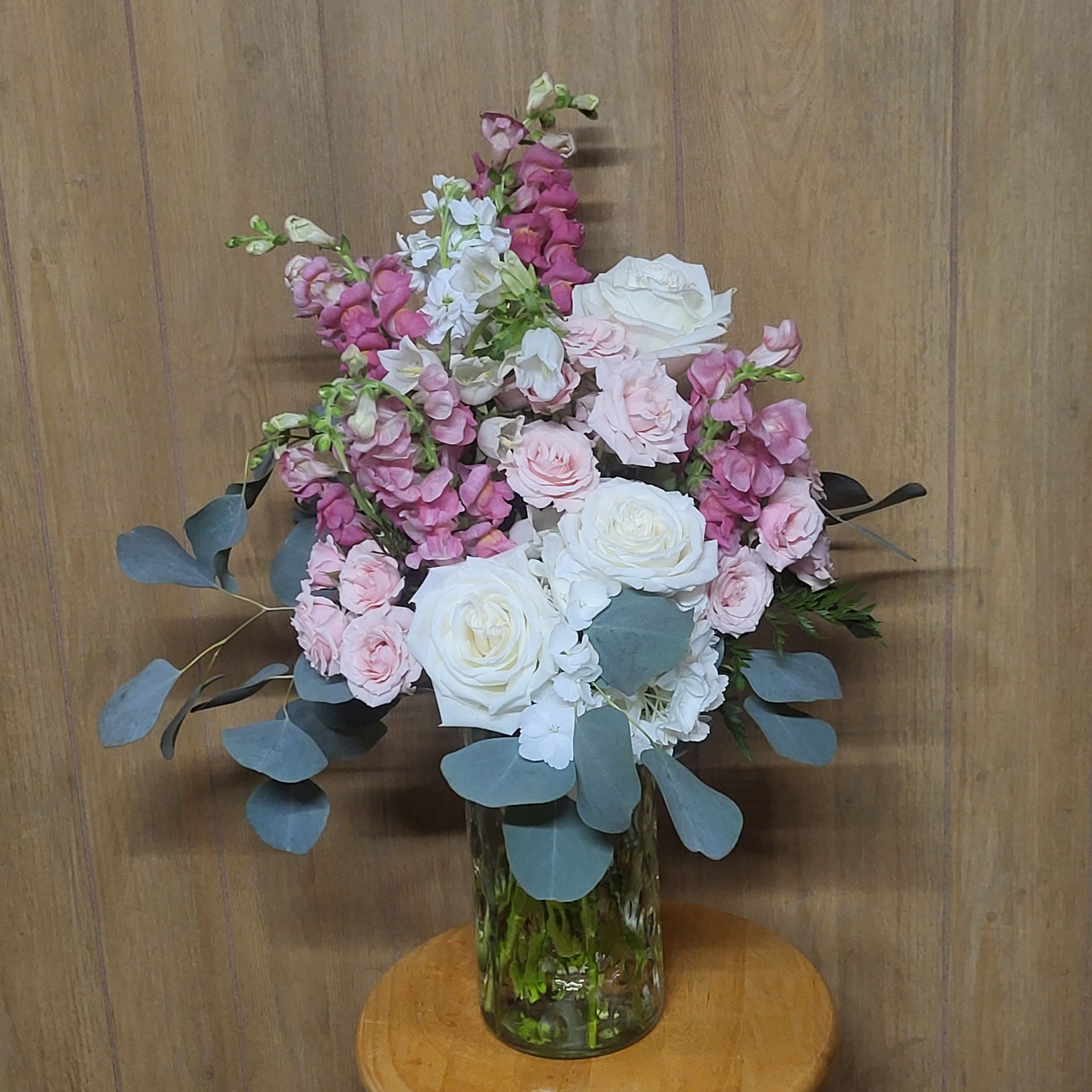 A bouquet of pink and white flowers on a wooden stool.