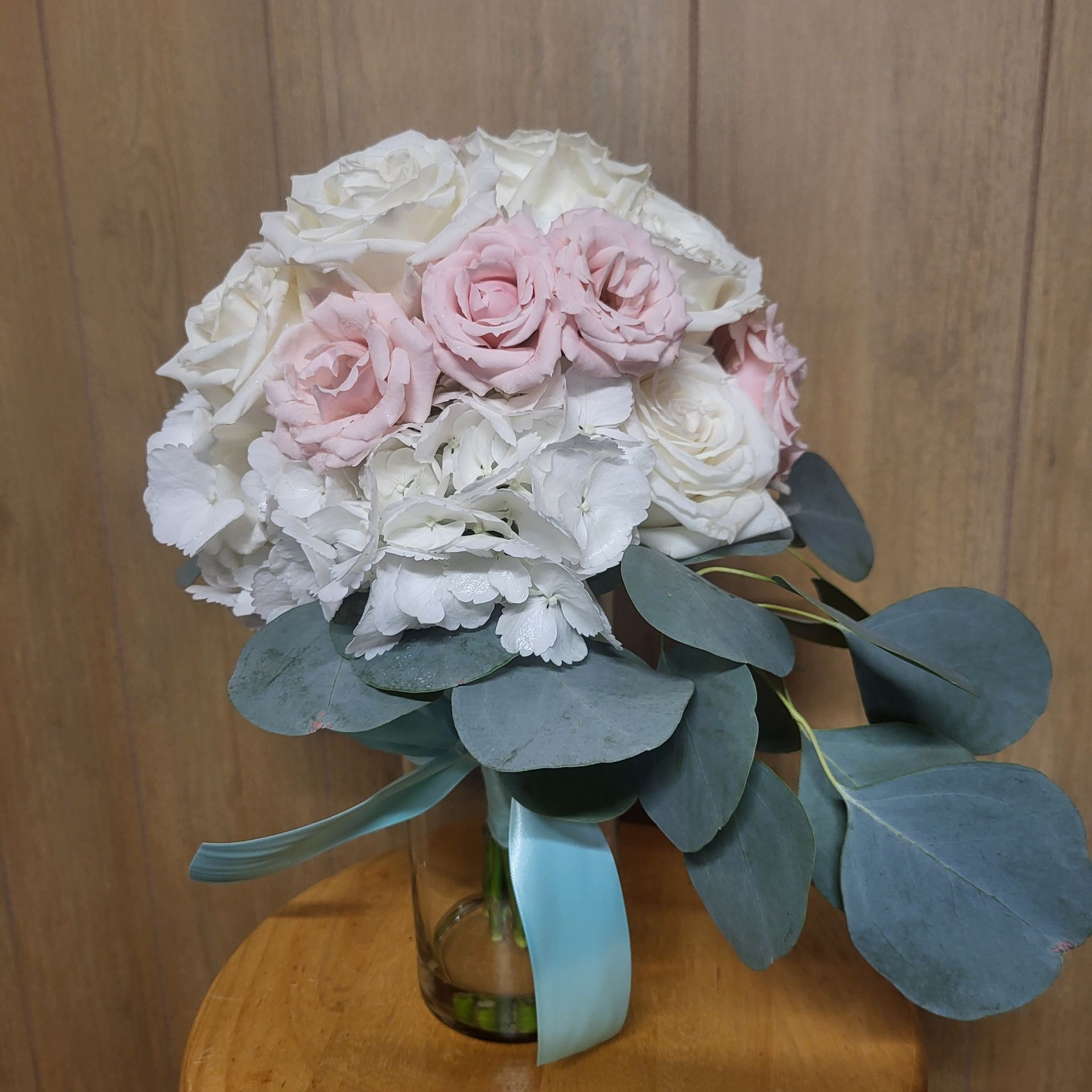 A bouquet of pink and white flowers on a wooden stool.
