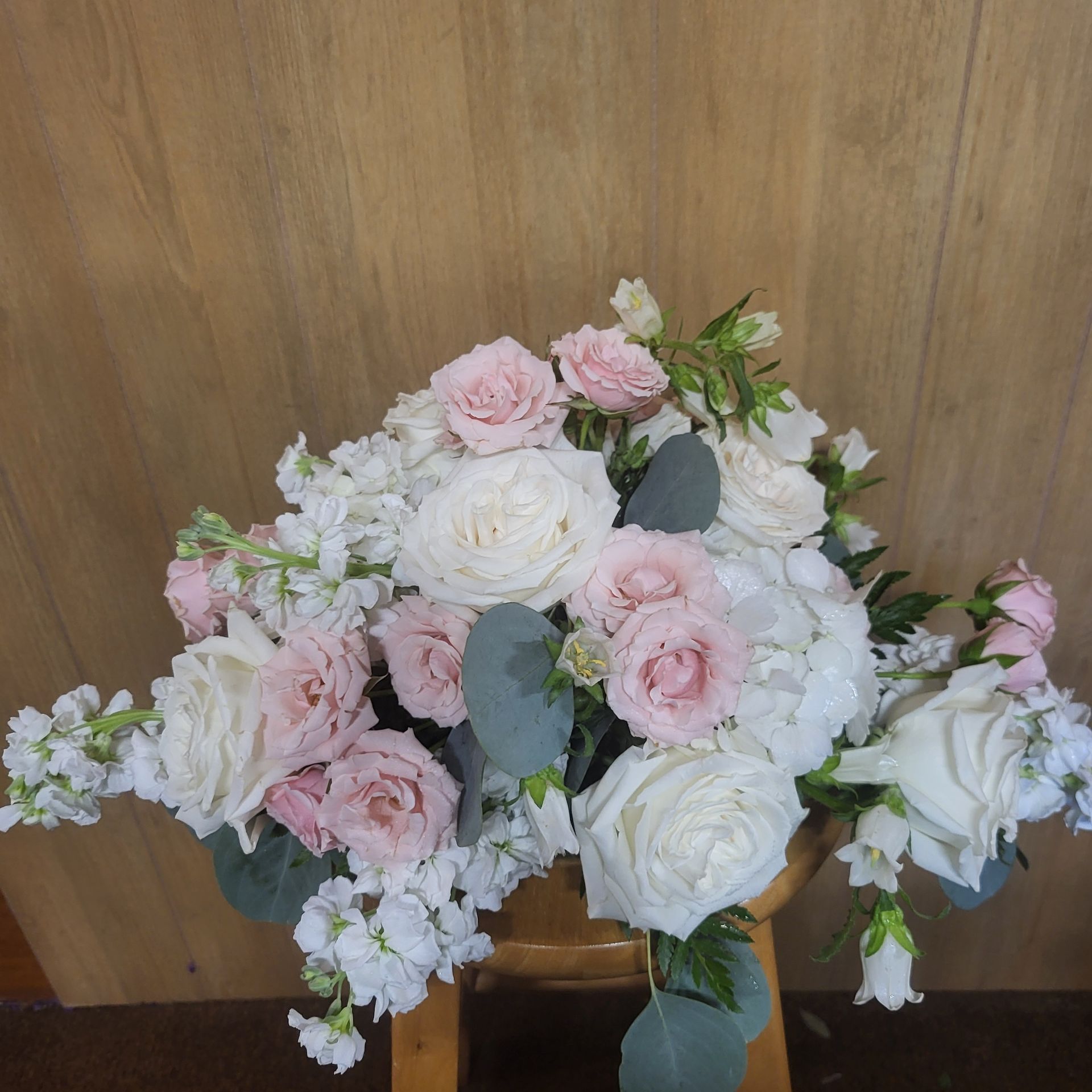 A bouquet of pink and white flowers on a wooden stool.