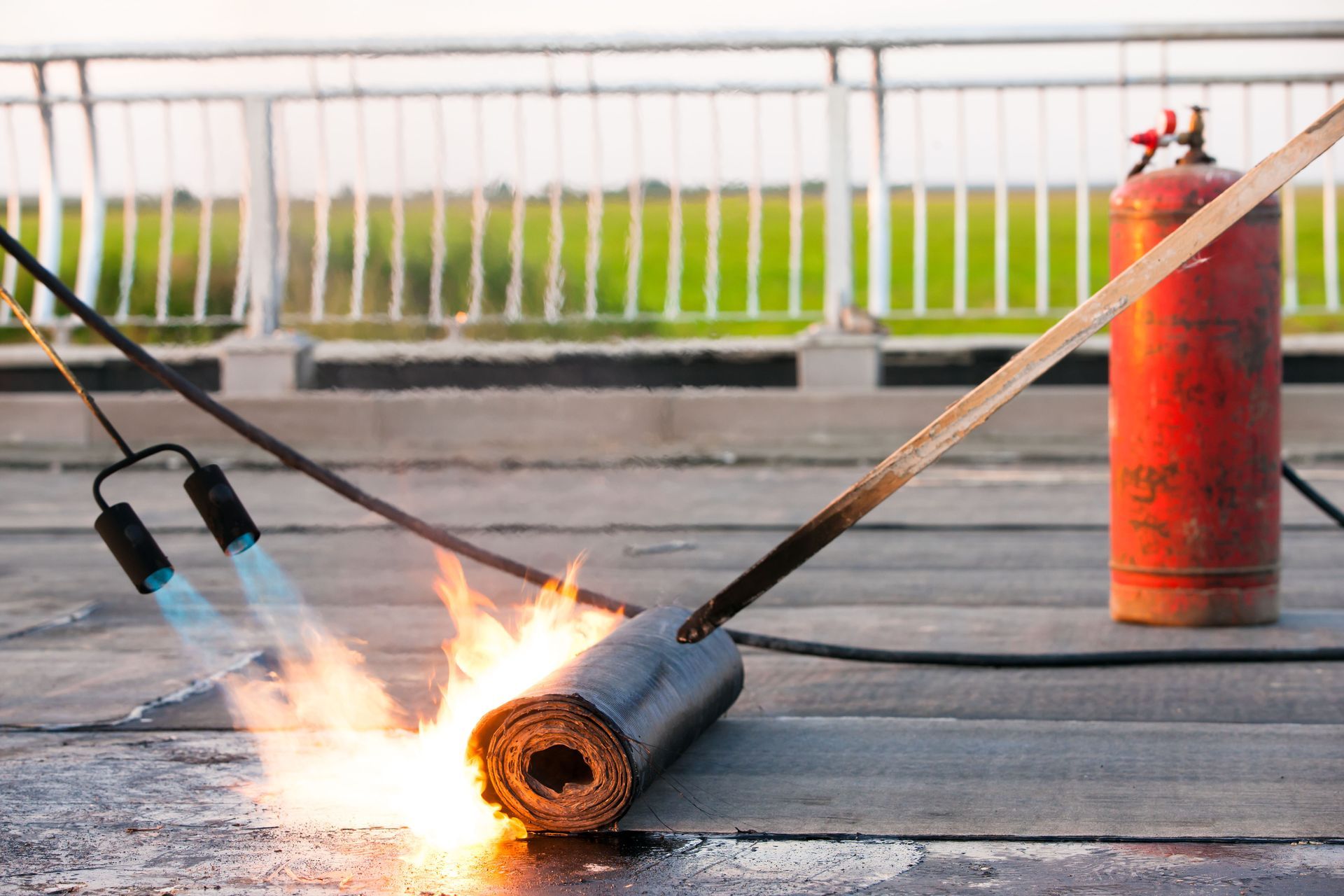 Roofing contractor using a torch to install a roll of roofing material on a deck.