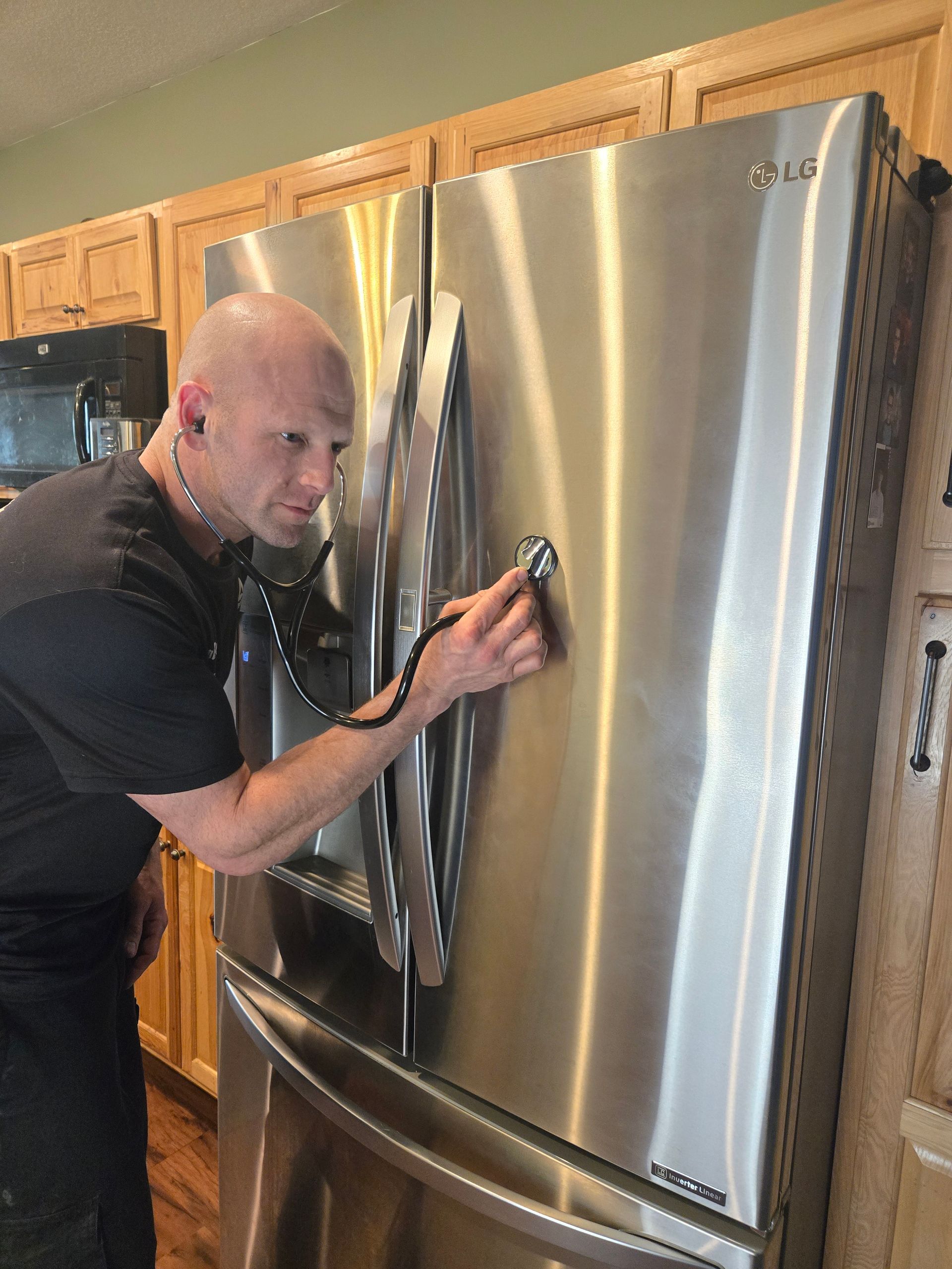 A man is looking at a stainless steel refrigerator in a kitchen.