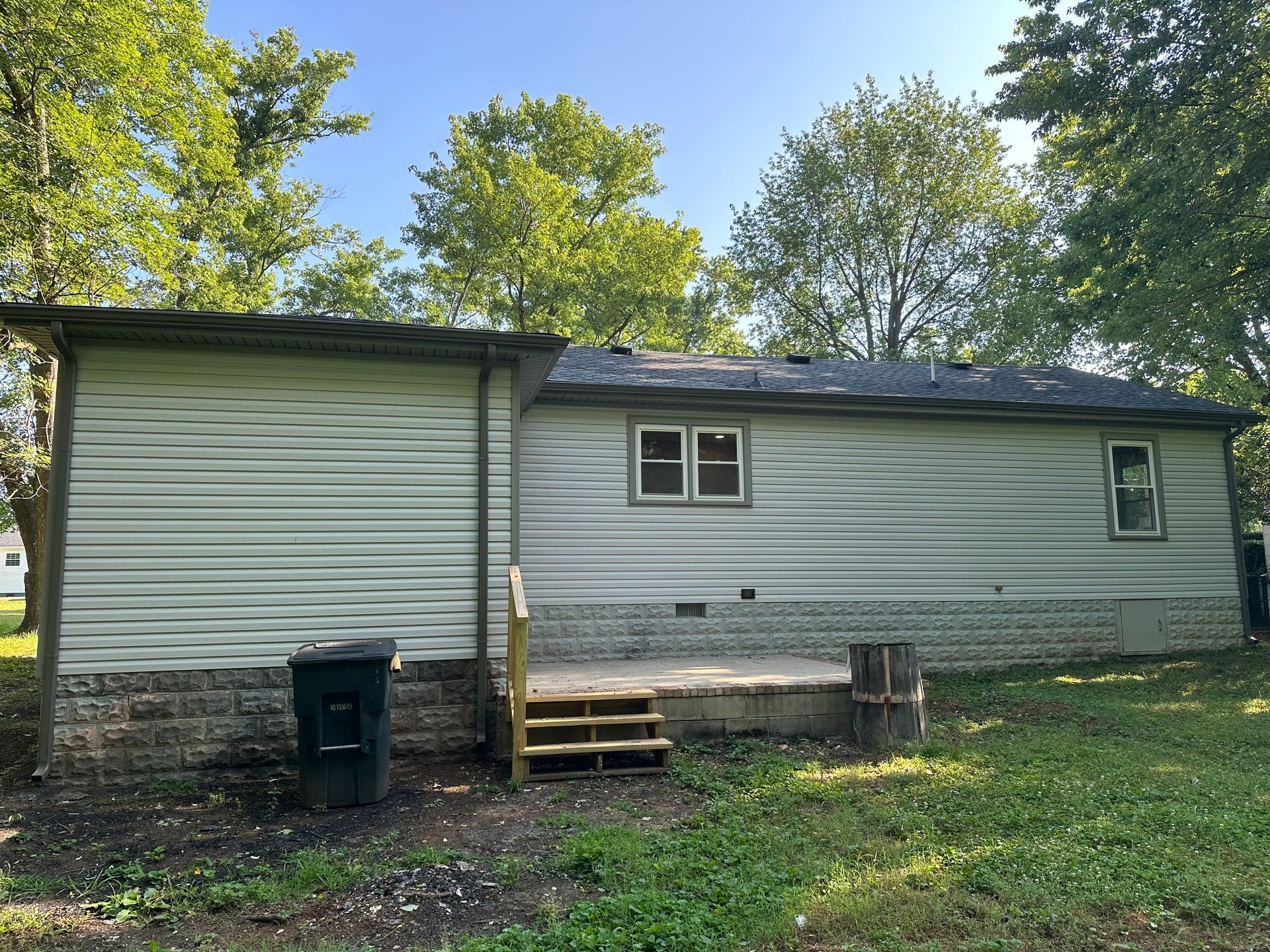 The back of a white house with a deck and stairs.