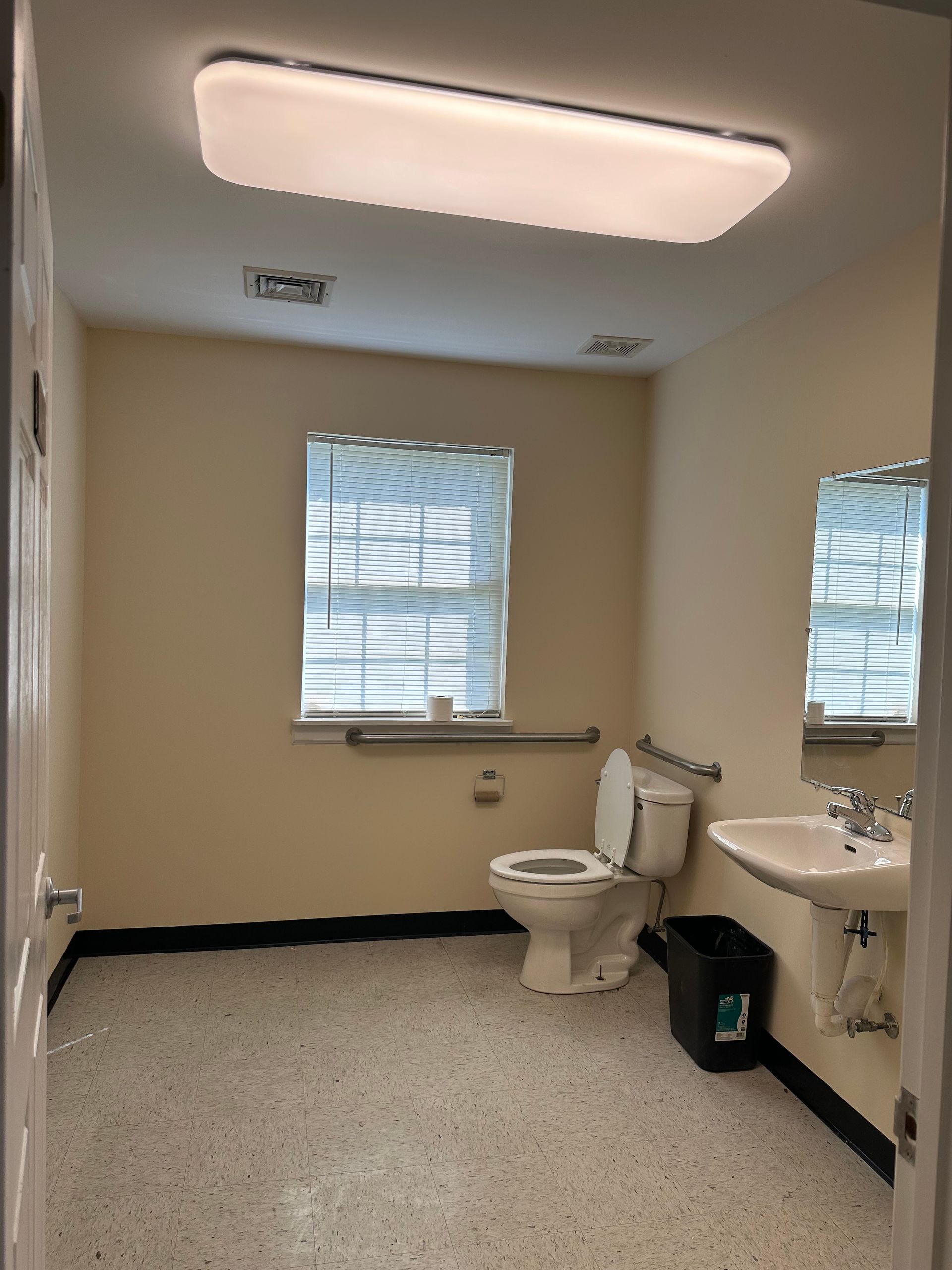 A bathroom with a toilet sink and two windows