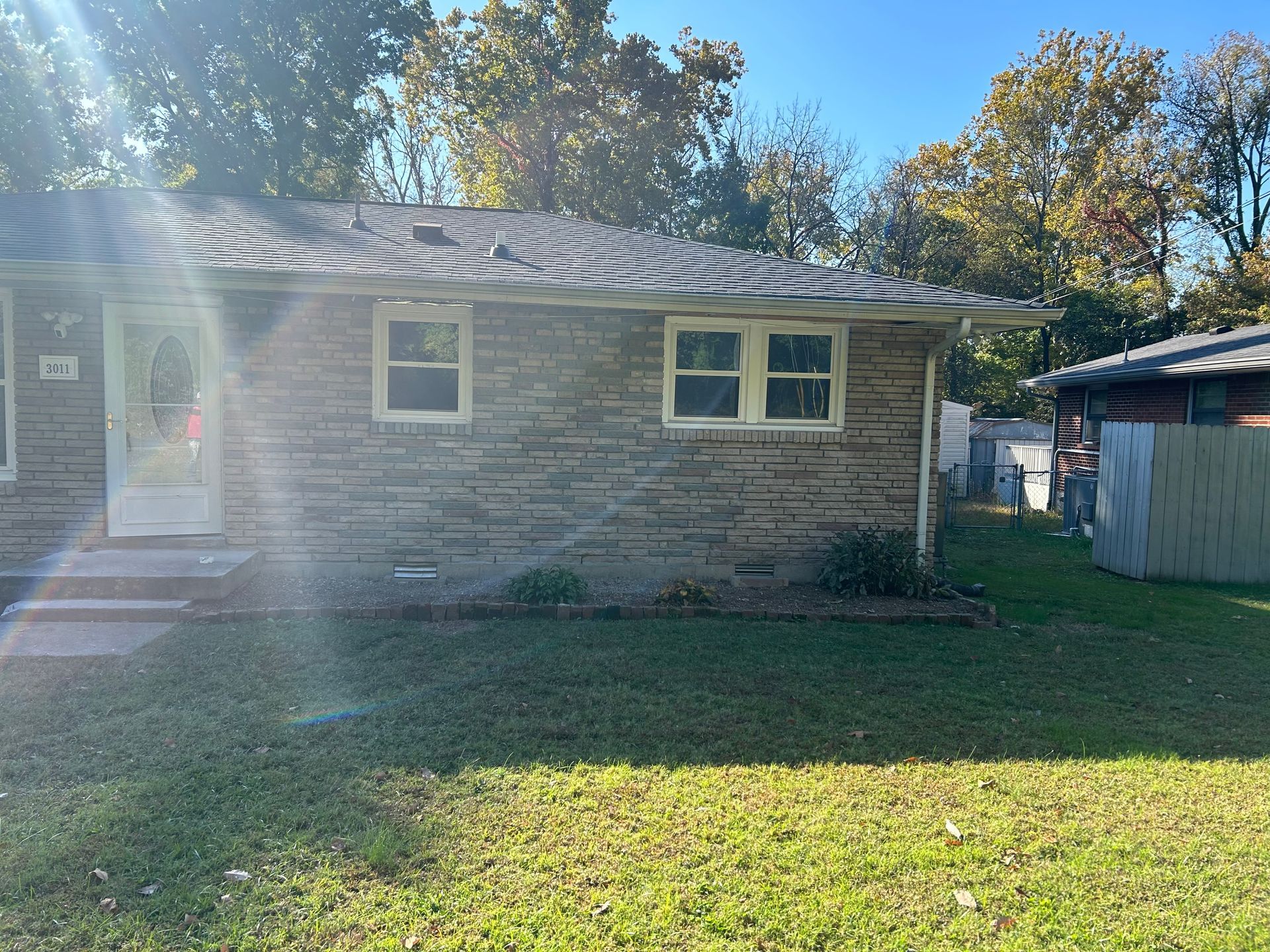 A small brick house with a roof and a lot of windows is for sale.