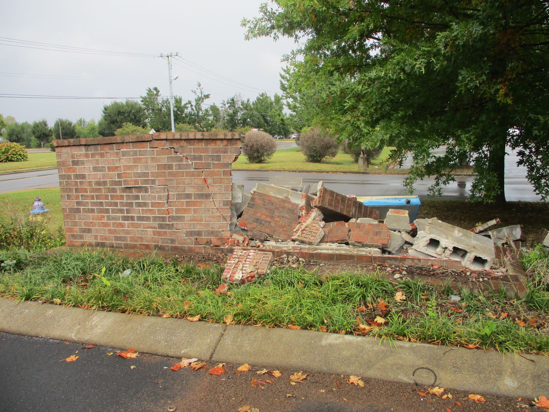 A pile of bricks is sitting on the side of the road next to a brick wall.