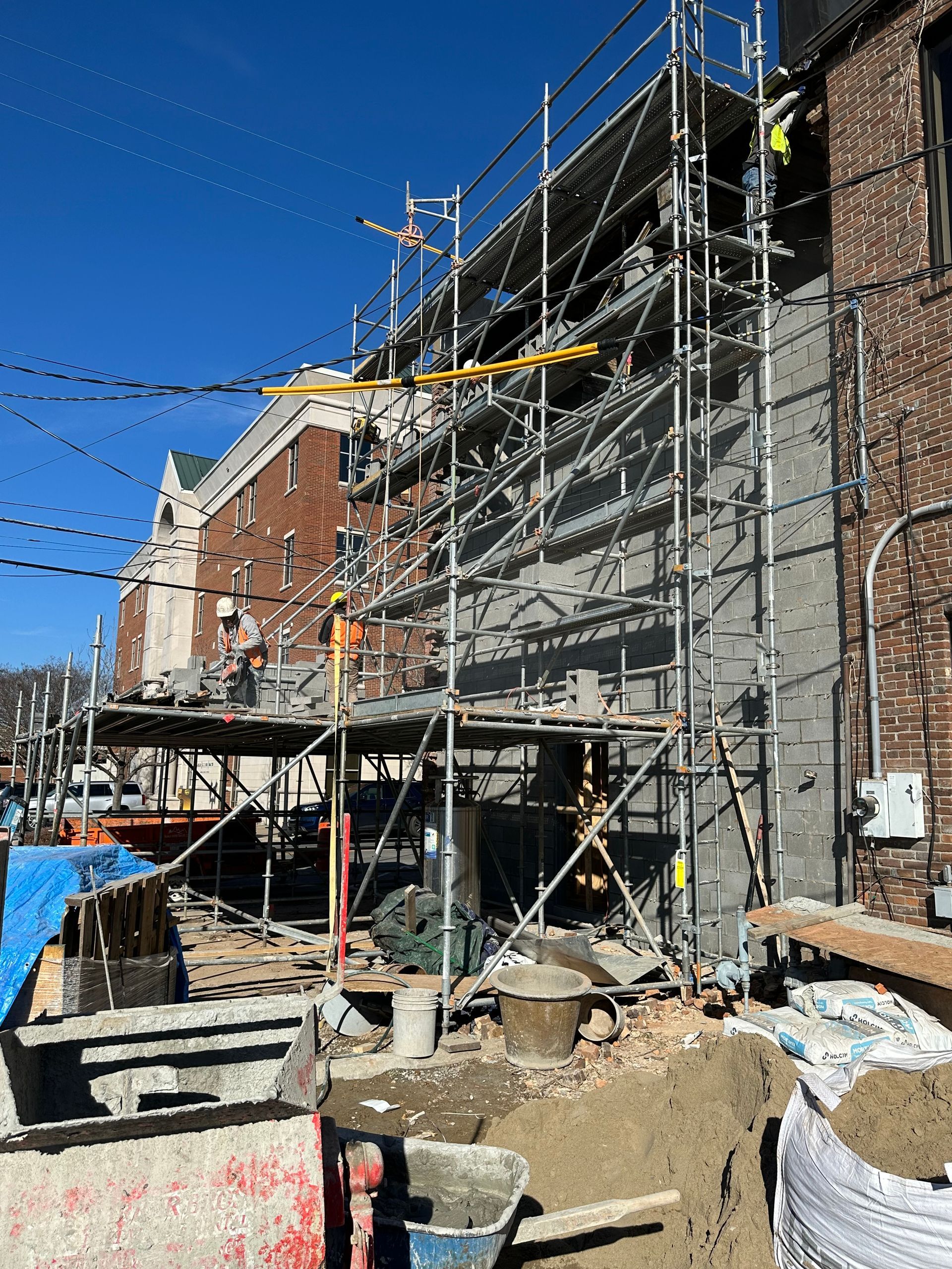 A construction site with scaffolding and a brick building in the background