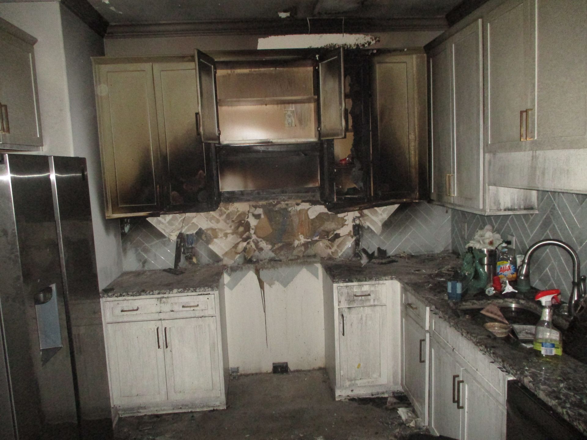 A kitchen with white cabinets and a stainless steel refrigerator