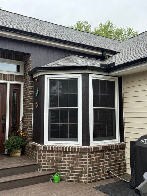 Beige house exterior with installed and waiting siding. Gutters and ladder nearby.