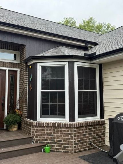 Beige house exterior with installed and waiting siding. Gutters and ladder nearby.