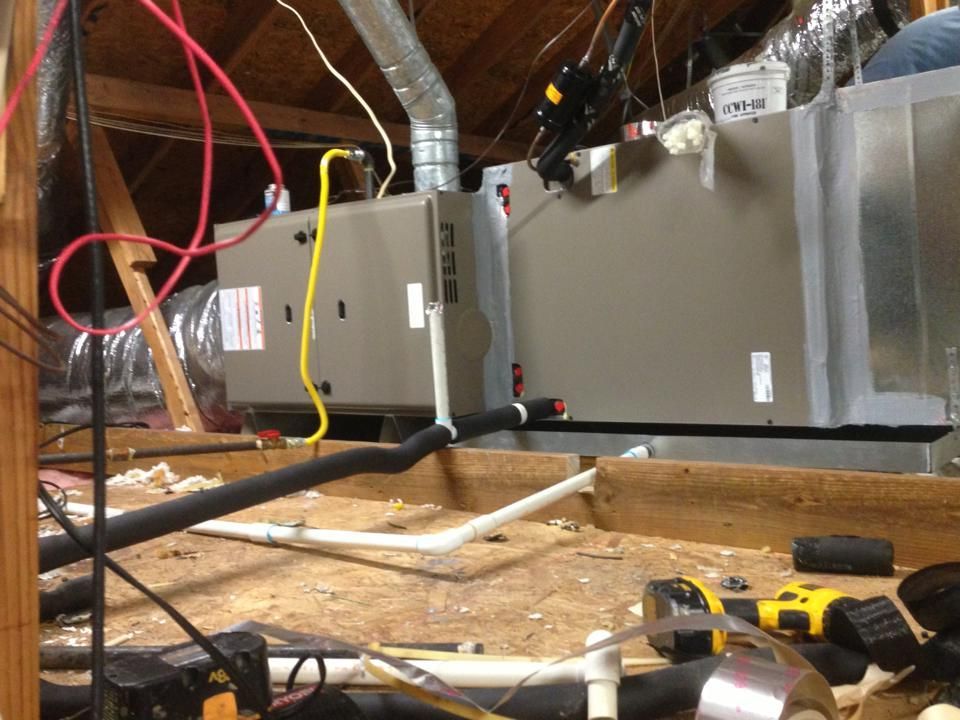 A man is working on an air conditioner in the attic