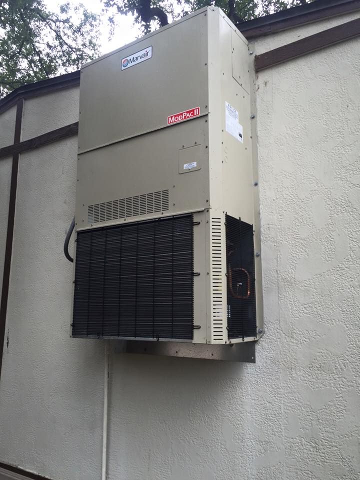 A large air conditioner is mounted on the side of a building.