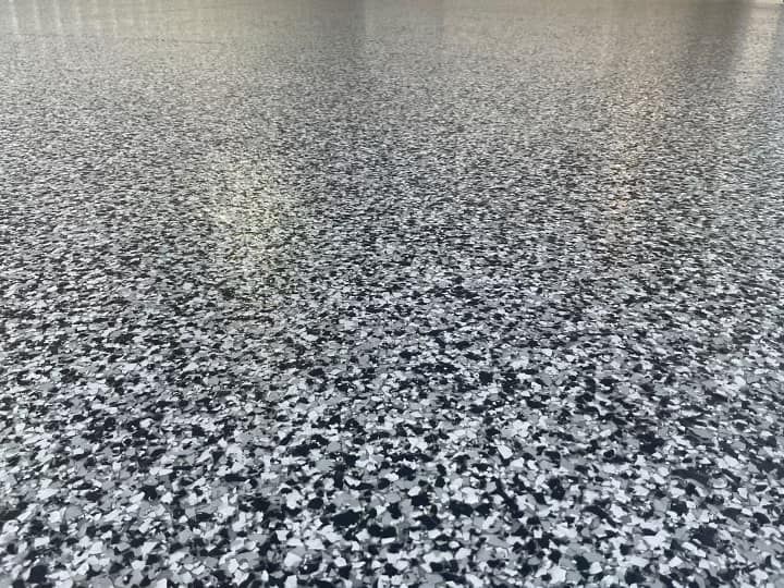 A paint roller is laying on a concrete floor.