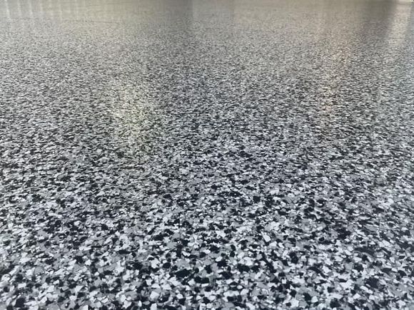 A paint roller is laying on a concrete floor.