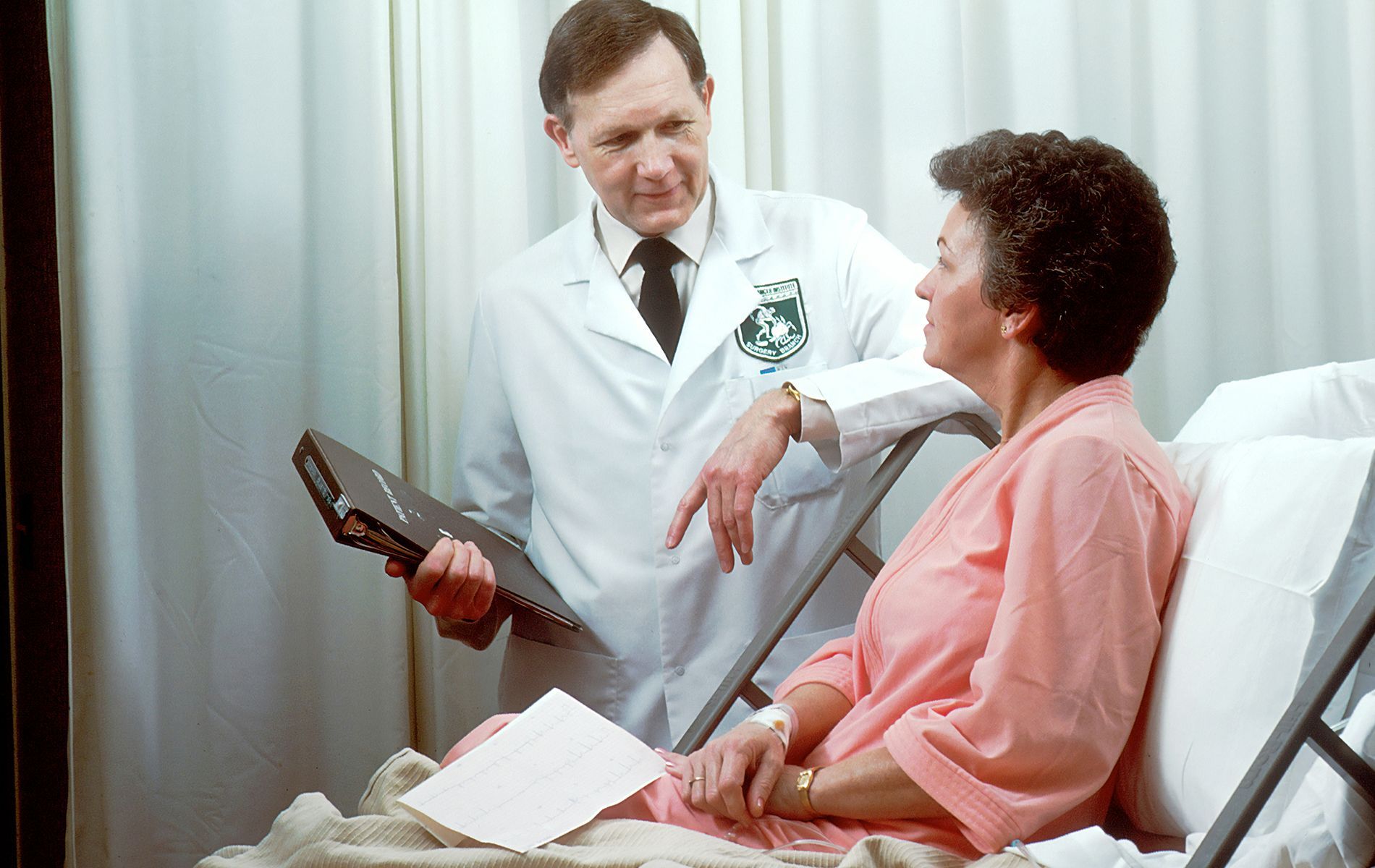 A doctor is talking to a patient in a hospital bed