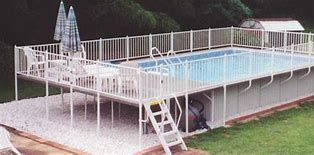 A large swimming pool with a deck and stairs in a backyard