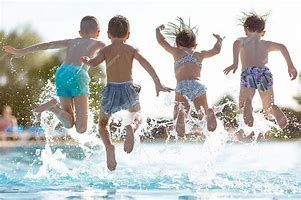 A group of children are jumping into a swimming pool