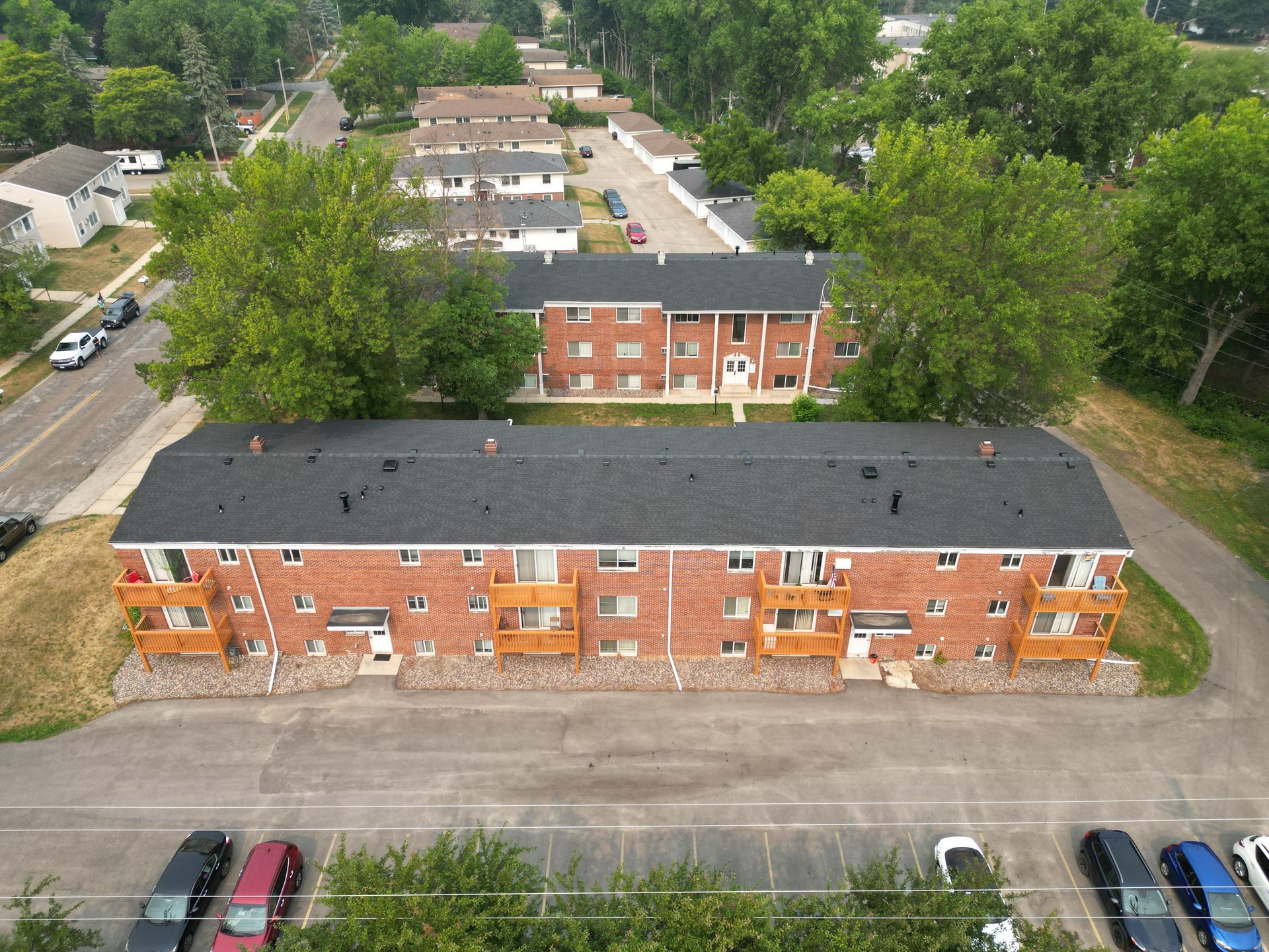 An aerial view of a brick apartment building with cars parked in front of it.