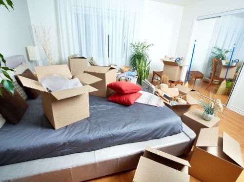 Boxes sit on a bed in a room, indicating a move