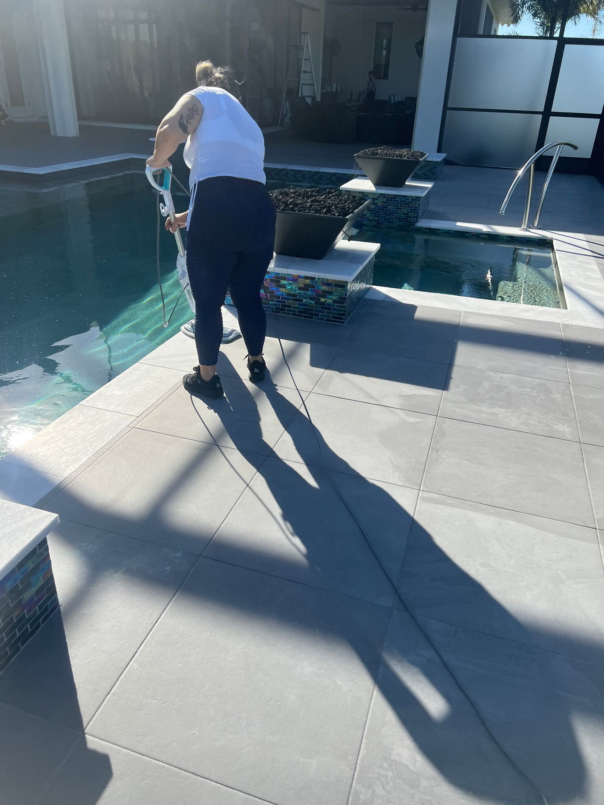 Lady cleaning the patio pool.