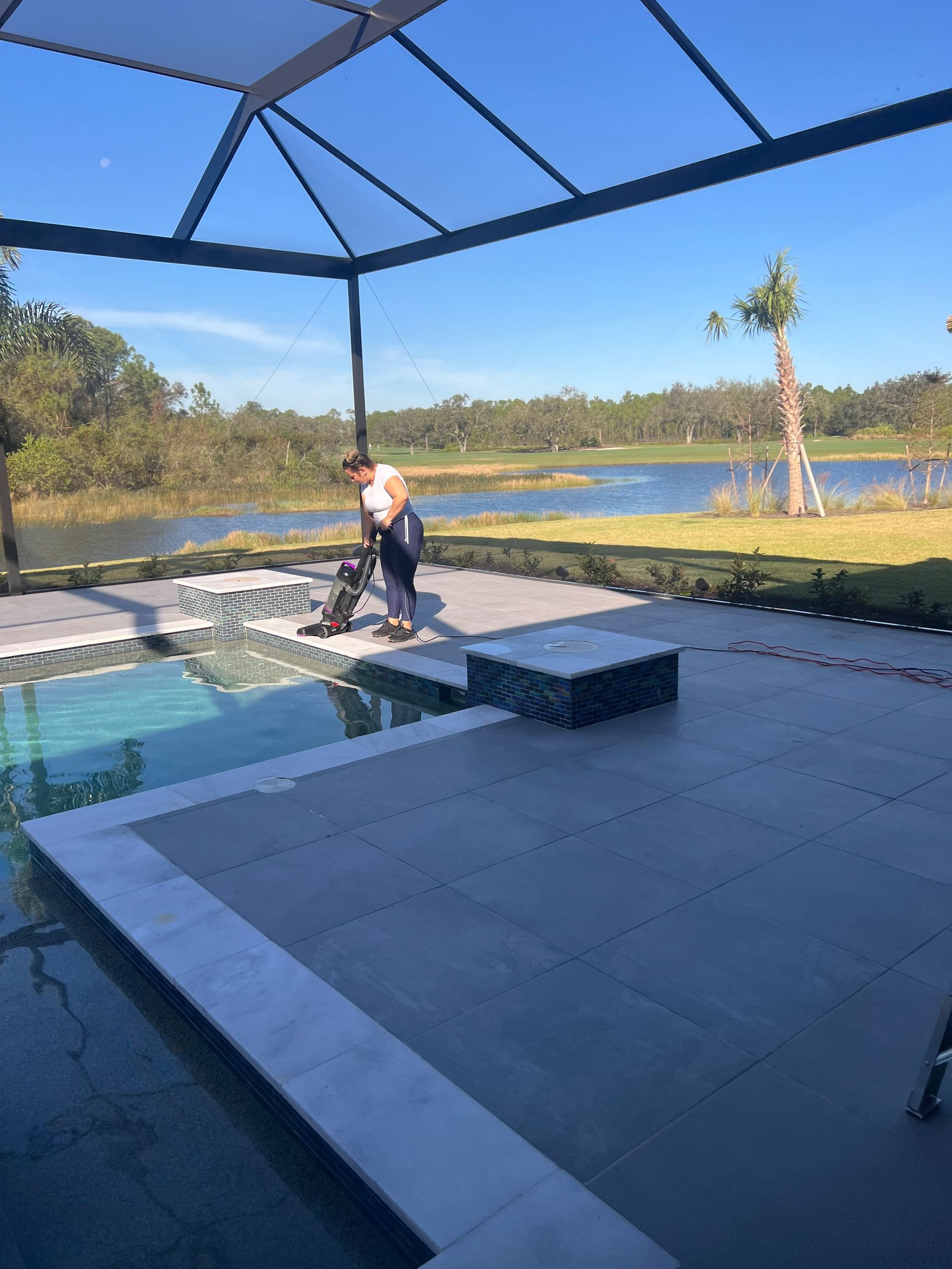 Lady vacuuming beside the patio pool.