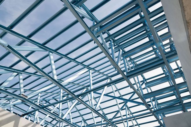 Blue steel roof trusses and glass panels forming a modern industrial ceiling structure