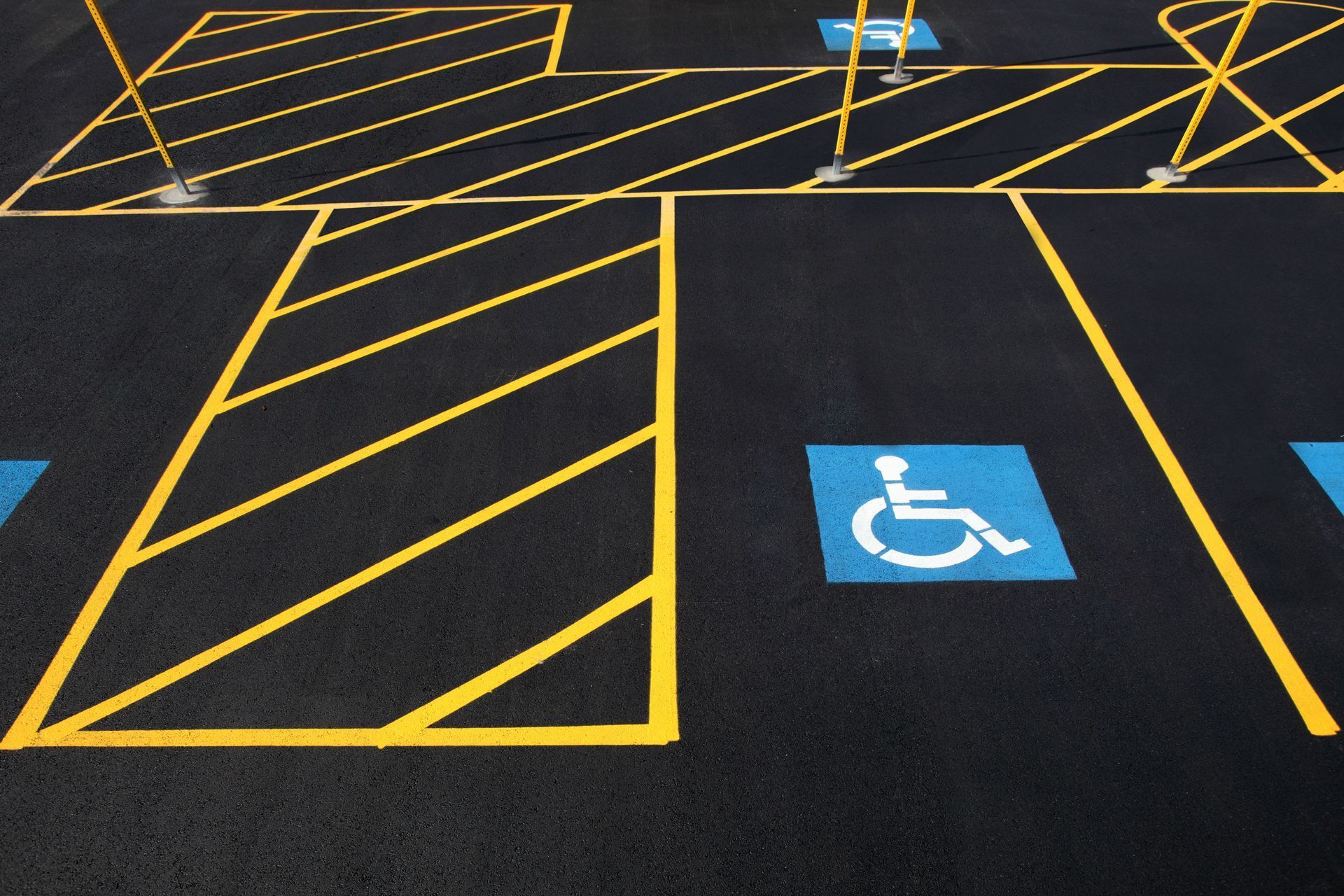 Parking lot with yellow painted lines and a blue accessible parking space.