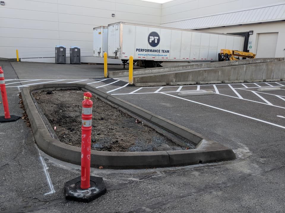 Loading dock area with a trailer, curb, and red safety bollards.