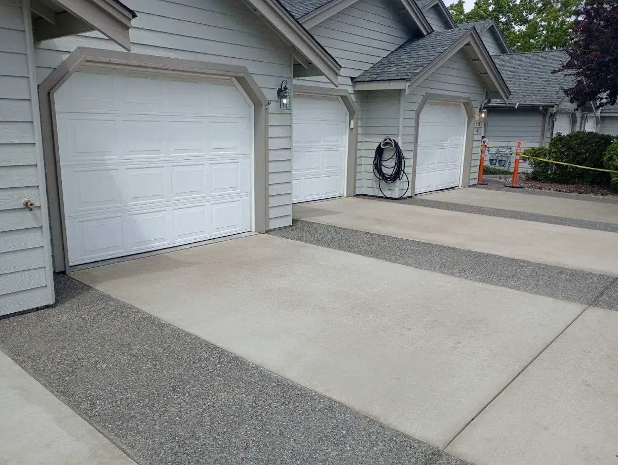 Row of attached garages with concrete driveways and gravel borders.