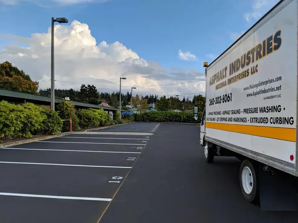 A white truck parked in a newly paved parking lot on a cloudy day.