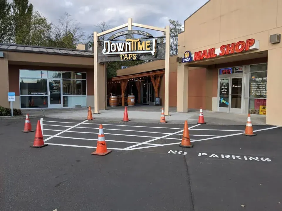 Exterior of Downtime Taps bar and Nail Shop. Orange cones delineate a painted area in front of the businesses.