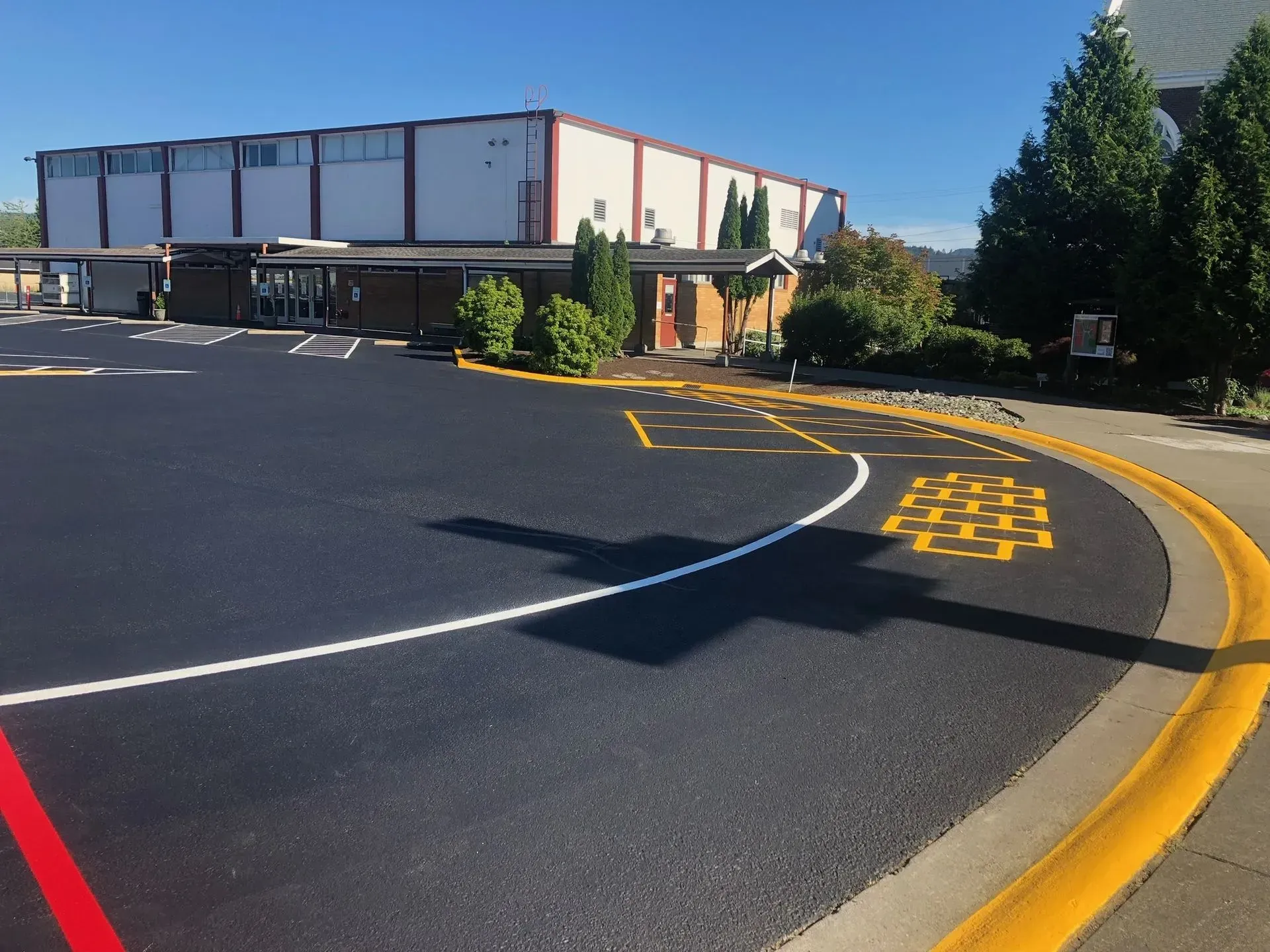 Paved school bus loading zone with yellow markings; building in background.