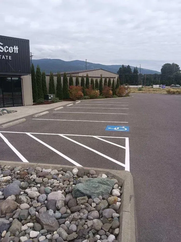 Parking lot with accessible parking spot, building, landscaping, and mountains in the background.