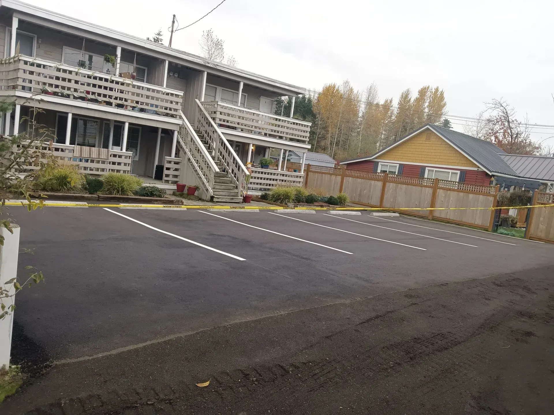 Apartment building with outdoor stairs and a freshly paved parking lot. Cloudy day.