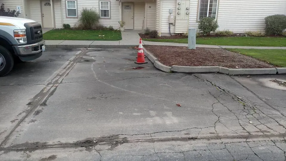 Parking lot with cracks, a truck, and a traffic cone.