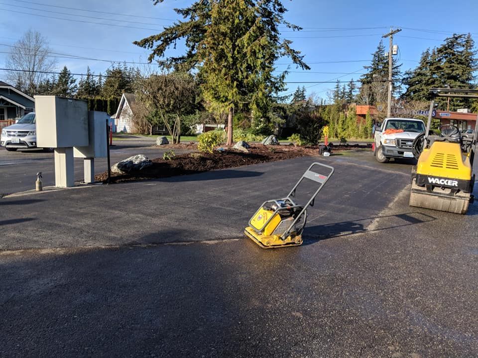 Asphalt paving in progress: asphalt, vibrating plate compactor, roller, truck.
