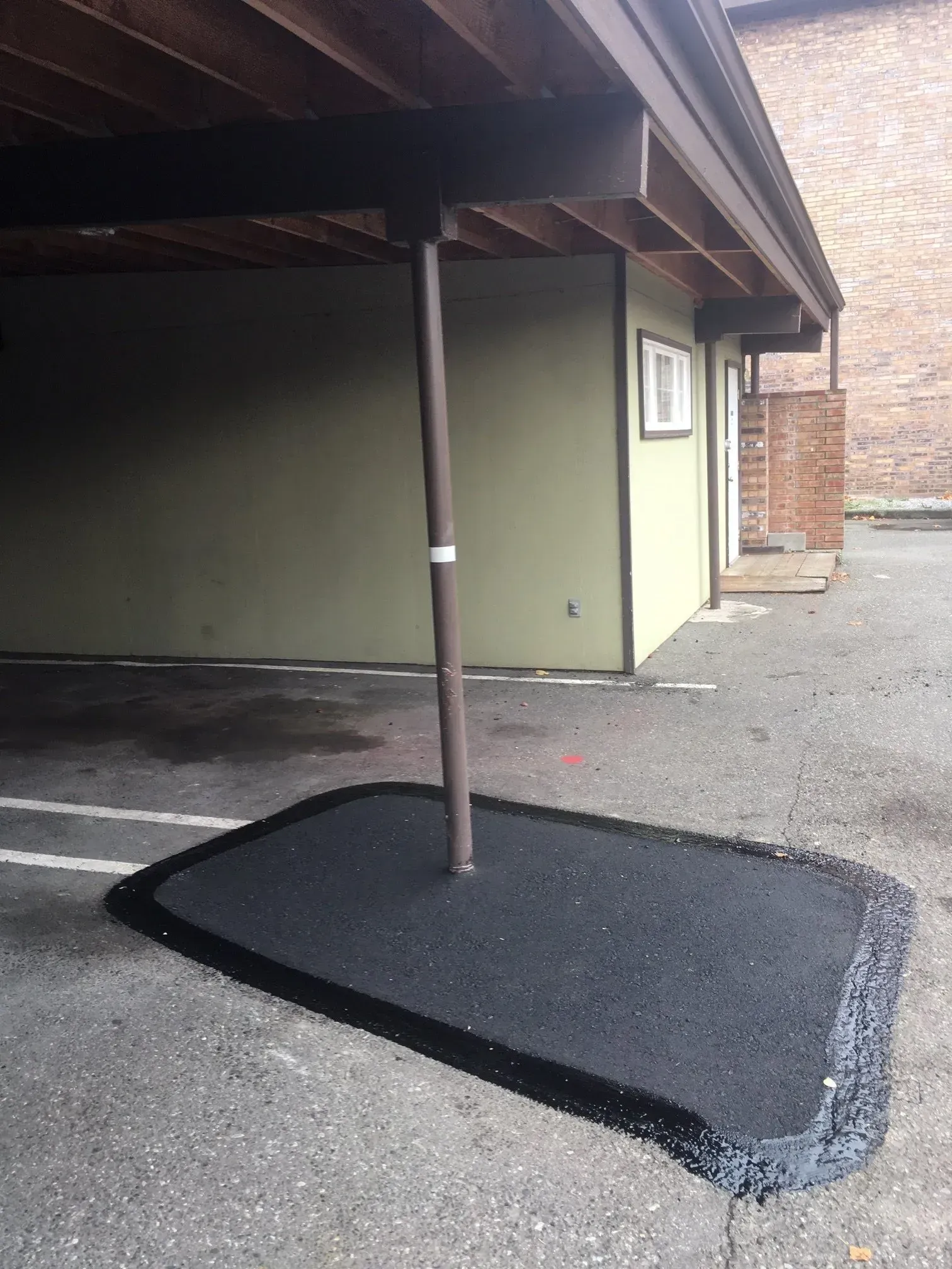 Parking area with a rubberized surface around a support pole.