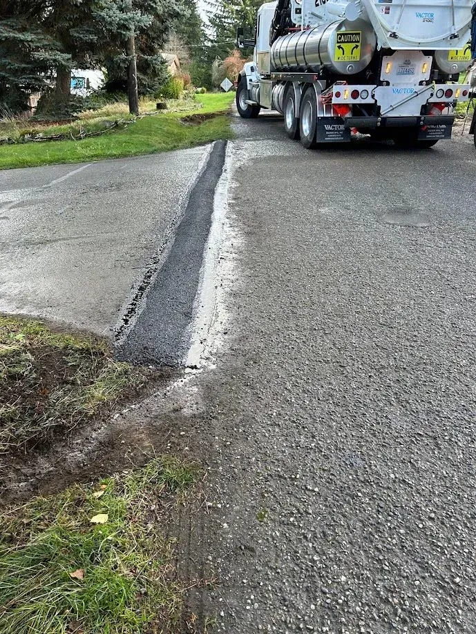 Asphalt being laid on a road with a cement truck in the background.