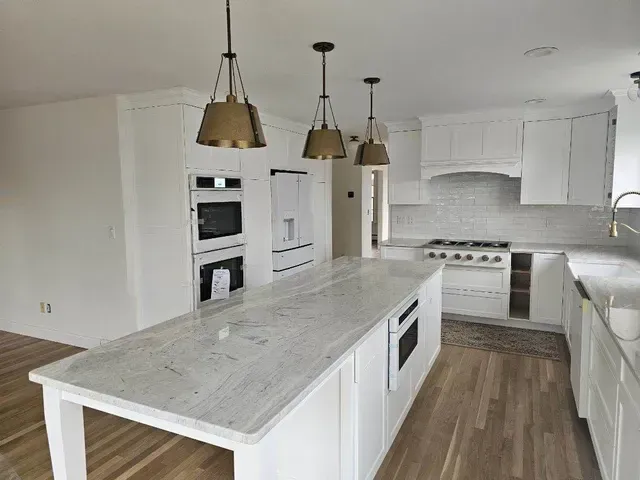 A kitchen with white cabinets and a large island in the middle.