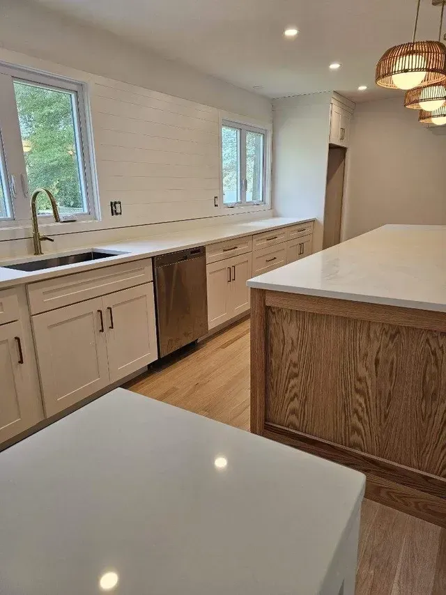 A kitchen with white cabinets, stainless steel appliances, and a large island.