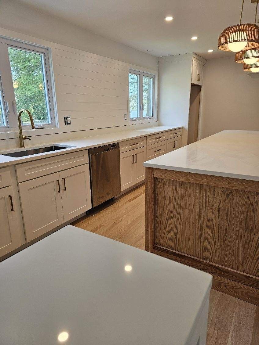 A kitchen with white cabinets, stainless steel appliances, and a large island.