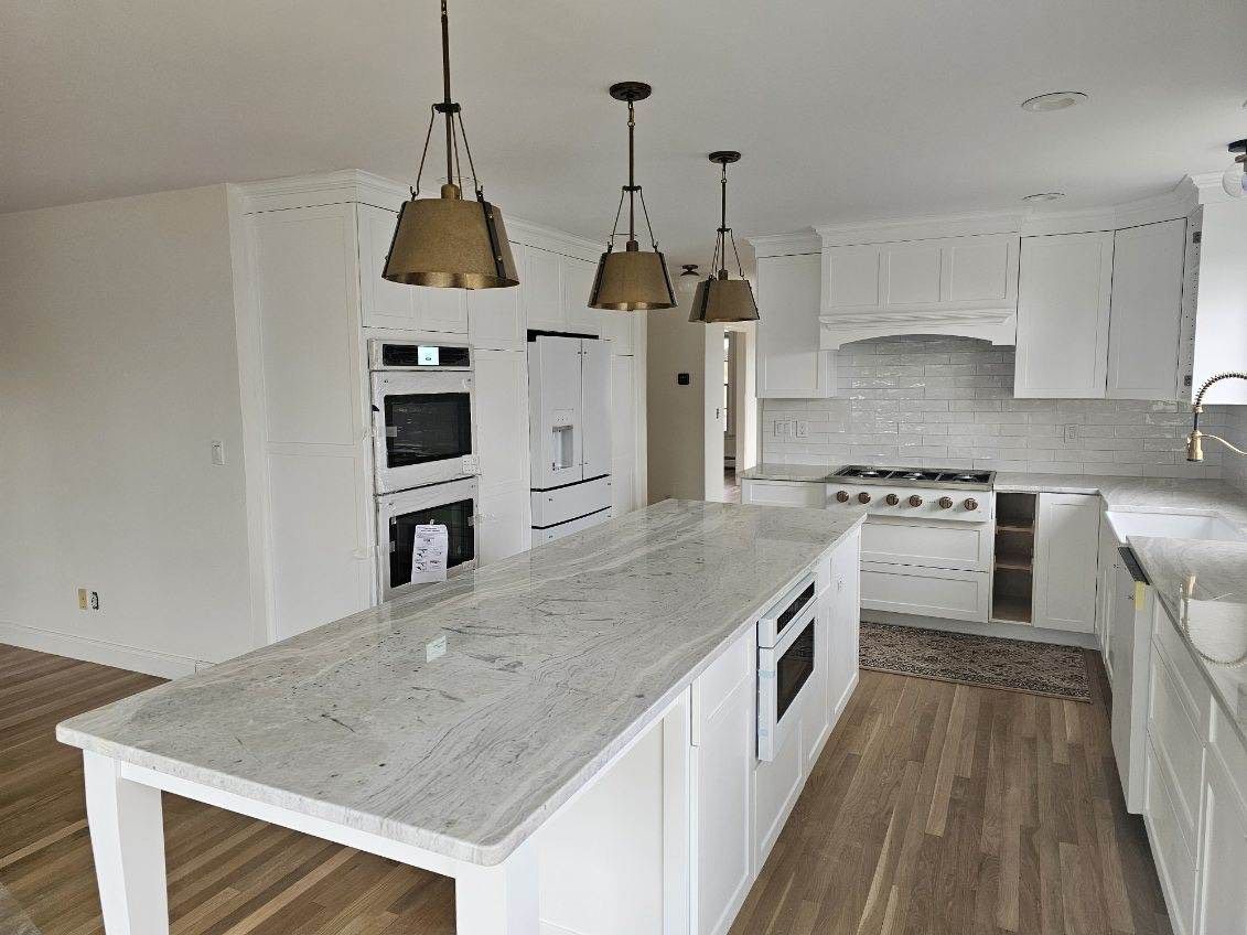 A kitchen with white cabinets and a large island in the middle.