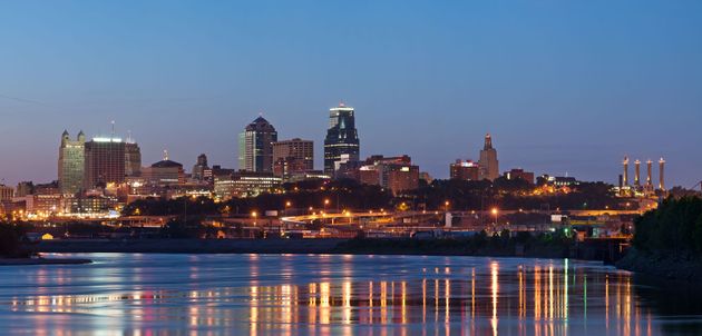 Night view of the Kansas City skyline reflecting on calm water; dark blue sky above.