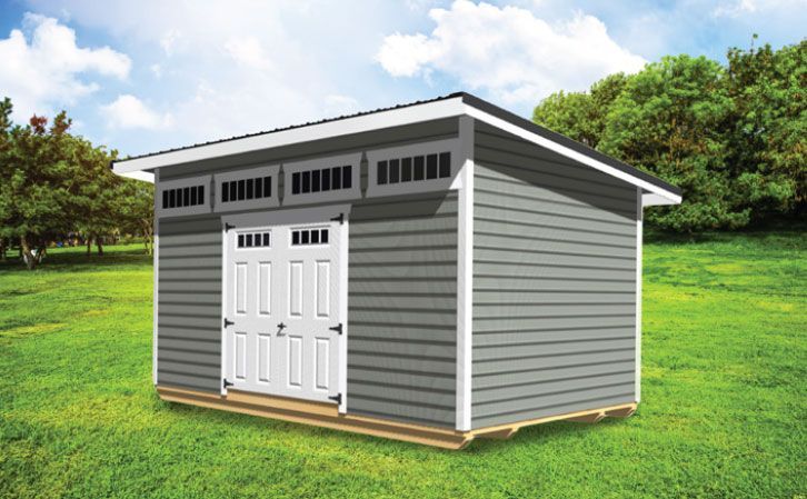 Gray shed with white trim and doors, on a grassy lawn with a blue sky background.