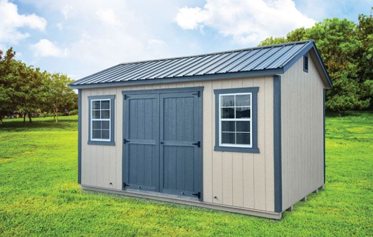 Tan shed with blue doors and trim, metal roof, on green grass.
