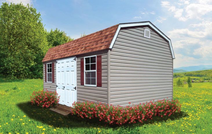 Gray storage shed with red roof and shutters, set in a green field with flowers and trees.